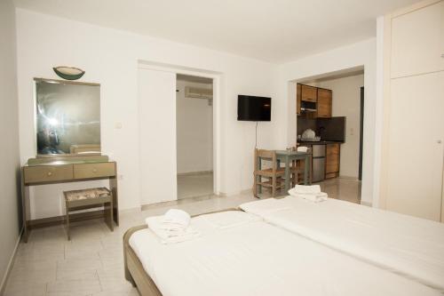 a white room with two beds and a television at Pegasos Studios in Karavadhos