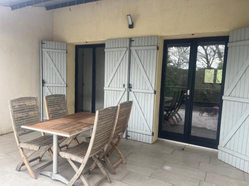 - une table et des chaises sur une terrasse avec portes coulissantes en verre dans l'établissement Appartement entier 1 à 4 personnes au calme avec parking gratuit, à Nîmes