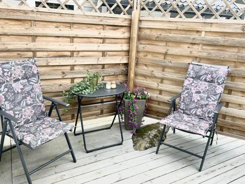 a patio with two chairs and a table with flowers at Lilla huset Bed & Breakfast - countryside guesthouse, free parking in Örebro