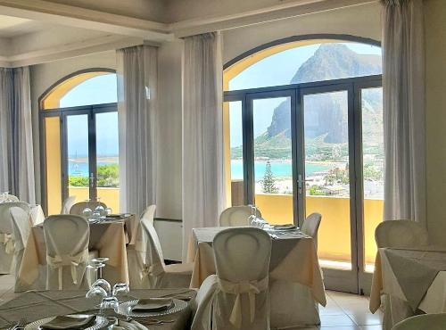 a dining room with tables and chairs and a large window at Hotel Panoramic in San Vito lo Capo