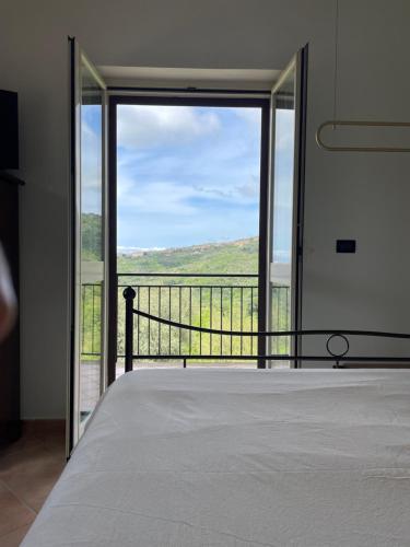 a bedroom with a bed and a large glass door at Pink House in Perdifumo