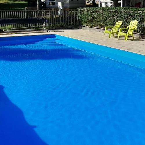 une piscine bleue avec deux chaises jaunes à côté dans l'établissement grote lodge safaritent 4, à Camurac