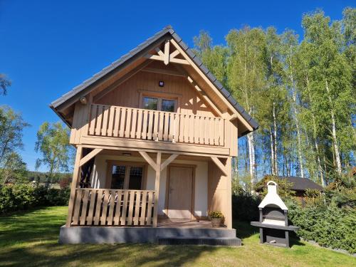 a tiny house with a porch and a balcony at Wiele Żurawi in Wiele