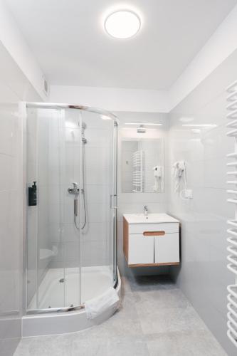 a white bathroom with a shower and a sink at Aparts & Hotel Garbarska in Radom