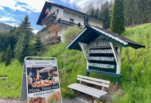 a building on a hill with a sign in front of it at Alpenpension Gasthof in Ratten