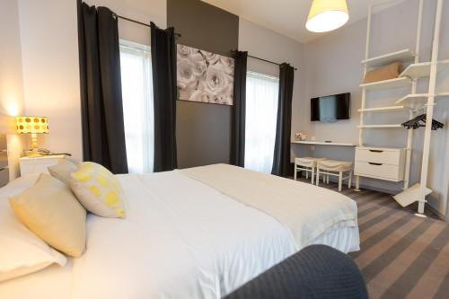 a bedroom with a large white bed and a desk at Cit'Hotel Les Alizes in Dinard