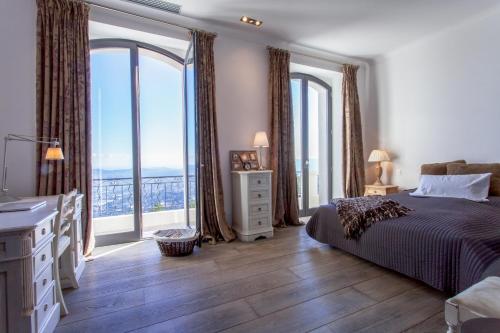 a bedroom with a bed and large windows with a view at Maison Saint Christophe in Grasse