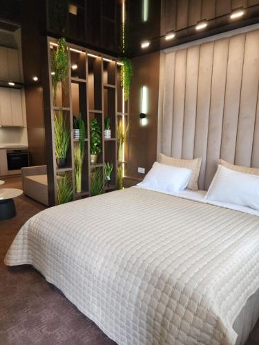 a bedroom with a large white bed with plants at Harmony Apartments in Podgorica