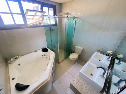 a bathroom with a tub and a sink and a toilet at Nossa Casa em Vilas - 70 m da areia - 6 Suítes in Lauro de Freitas