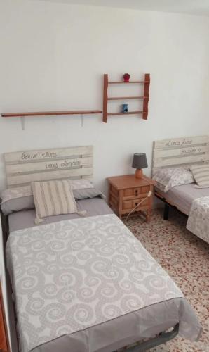 a bedroom with two beds and a night stand with a table at Casa Elviras in Alcossebre