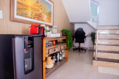 a kitchen with a refrigerator and a shelf with condiments at Nossa Casa em Vilas - 70 m da areia - 6 Suítes in Lauro de Freitas