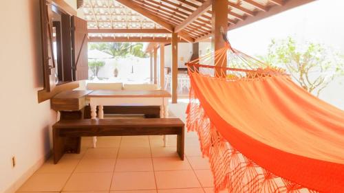 a hammock in a room with a table and a window at Nossa Casa em Vilas - 70 m da areia - 6 Suítes in Lauro de Freitas