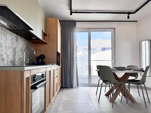 Una cocina con mesa y sillas y una ventana. en Exclusive Retreat off the Sea Front Promenade, en Il-Gżira