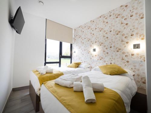 a bedroom with two beds with yellow and white sheets at Pensión Spa Cruceiro de Pedrouzo in O Pedrouzo