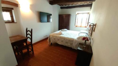 a bedroom with a bed and a table and two windows at Agriturismo La Taverna in Sovicille
