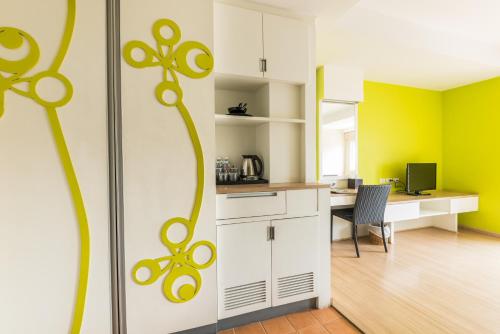 a kitchen with yellow and white cabinets and a desk at Lantana Pattaya - SHA Extra Plus in Pattaya North