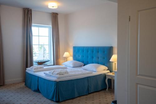 a large bed with a blue headboard in a room at Hotel Villa Tripaldi in Schönberg in Holstein