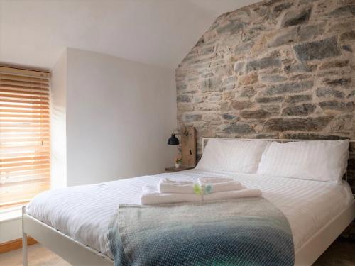 ein Schlafzimmer mit einem großen Bett mit einer Steinwand in der Unterkunft Charming 2 bed Escape in Snowdonia National Park ! Nr Betws y Coed in Betws-y-coed