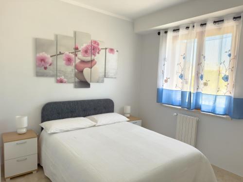 Un dormitorio con una cama blanca y flores rosas. en Casa Romualdo, en Monopoli