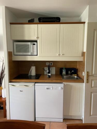 La cuisine est équipée de placards blancs, d'un four micro-ondes et d'un évier. dans l'établissement Séjour 4 personnes - Pays Basque, à Uhart-Cize