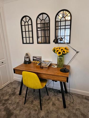 a desk with a yellow chair and a lamp and some mirrors at Braveheart Haven: 4BD Retreat with Hot Tub in Stirling