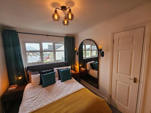 a bedroom with a bed with a mirror and a window at Braveheart Haven: 4BD Retreat with Hot Tub in Stirling