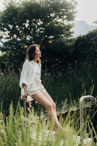 a woman sitting on a pole in the grass at Boutique-Hotel Ballguthof am Golfplatz in Lana