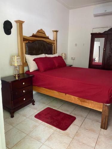 a bedroom with a large bed with a red bedspread at Woody Town Centre Apartment in Port Antonio