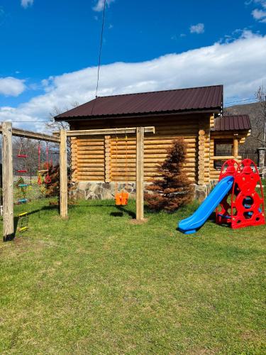 a playground with a slide and a log house at Eco House Borjomi in Borjomi