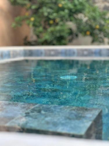 a pool of blue water with a stone ledge at Can Vilàs in Muro
