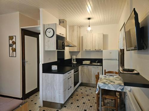 une cuisine avec des placards blancs et une horloge murale dans l'établissement MF n 3, à Cazaubon