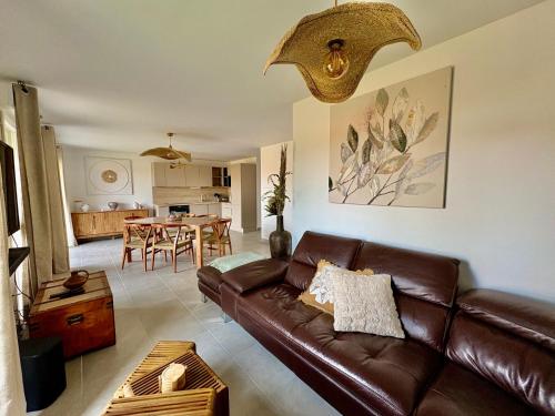 a living room with a brown leather couch and a table at Appartement 2 chambres à 600m de l'Océan in Mimizan-Plage