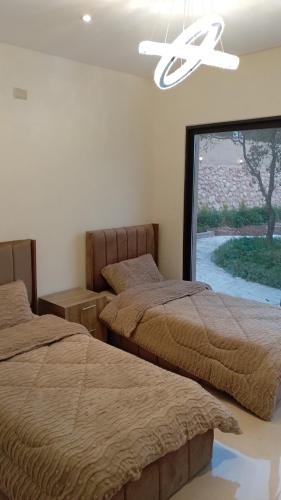 a bedroom with two beds and a large window at Munifah Grand Hills Chalet and Farm in Jurf ad Darāwīsh