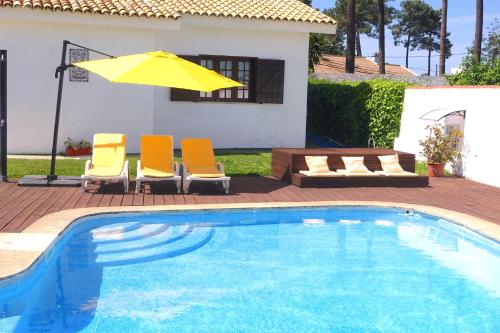 einen Pool mit Stühlen und einem gelben Sonnenschirm in der Unterkunft Villa near Beach & Lisbon in Corroios
