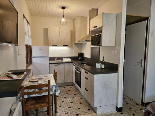 - une cuisine avec des appareils blancs, une table et des chaises dans l'établissement MF n 4, à Cazaubon