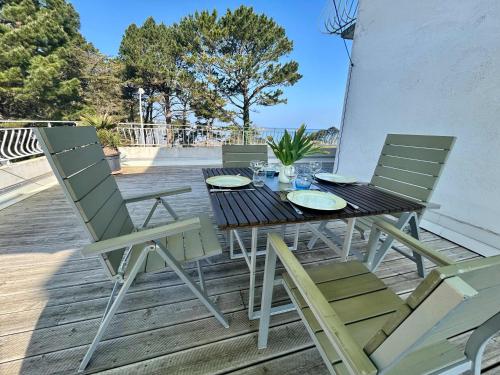 une table et des chaises assises sur une terrasse dans l'établissement Seafront flat with indoor pool with stunning views, à Plestin-les-Grèves