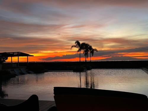 a sunset over a body of water with palm trees at Luxurious Modern Cozy Manila Bayview Pool View 1 2 3 Bedrooms Near Manila Airports Okada Solaire MOA in Manila