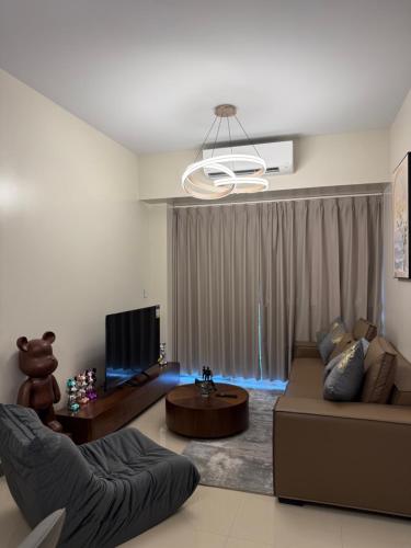 a living room with a couch and a tv at Luxurious Modern Cozy Manila Bayview Pool View 1 2 3 Bedrooms Near Manila Airports Okada Solaire MOA in Manila