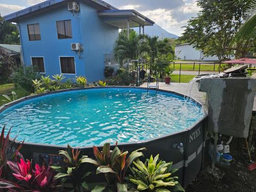 a large swimming pool in front of a blue house at Full equipado, WiFi, AC, vista volcán, 1er piso in Fortuna
