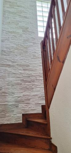 a wooden staircase with a brick wall at Maison Paloumères in Ledeuix
