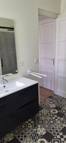 a bathroom with a sink and a mirror and a door at Maison Paloumères in Ledeuix