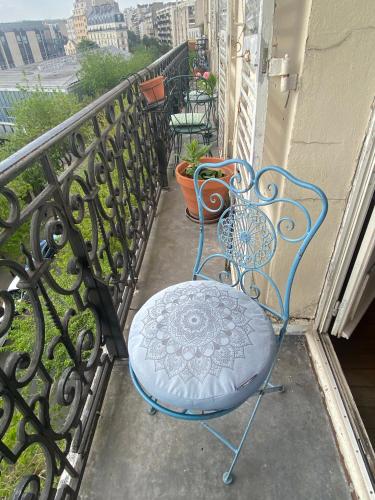 une chaise bleue assise sur un balcon avec un balcon dans l'établissement Chambre avec vue Montmartre & Tour Eiffel, à Paris