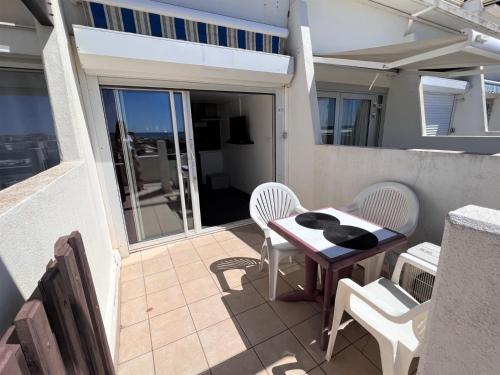 d'un petit balcon avec une table et des chaises sur la terrasse. dans l'établissement VILLAGE NATURISTE - CAP d'AGDE - PORT NATURE 2 - VUE MER - COURSIVE, au Cap d'Agde