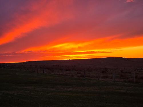 a sunset over a field with a fence at Squealing Pig Bothy in Bragor