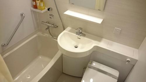 a white bathroom with a sink and a toilet at Grand Hotel Kanachu Hiratsuka in Hiratsuka