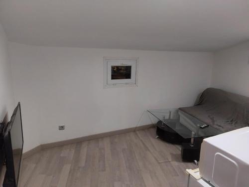 Cette petite chambre blanche comprend un lit et une télévision. dans l'établissement Studio à louer sur Miramas, à Miramas