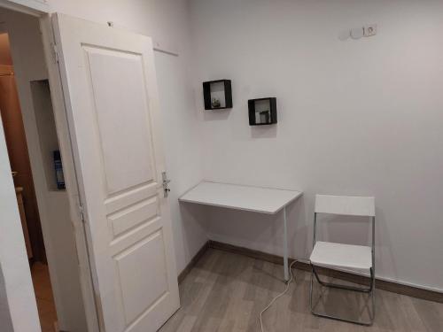 Cette chambre blanche dispose d'un bureau et d'une chaise blancs. dans l'établissement Studio à louer sur Miramas, à Miramas
