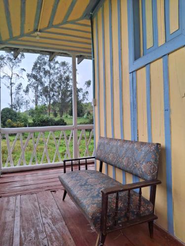 a bench sitting on the porch of a house at Refugio Paramo Trek Murillo in Murillo