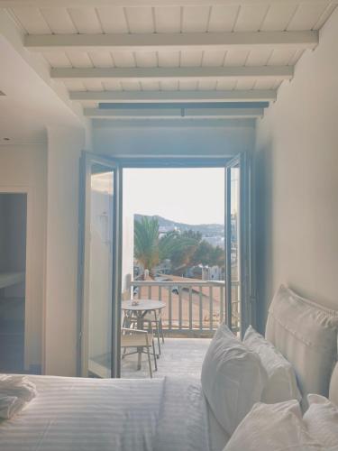 a bedroom with a bed and a balcony with a table at Fabrikas in Mýkonos City