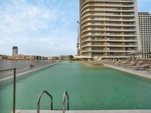 a swimming pool in front of a tall building at Utra Lux Large 1 BR with Sunset Views and Private Beach in Dubai